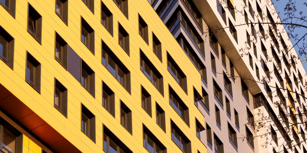 2111506655 Yellow modern ventilated facade with windows. Part of urban real estate. Fragment of a new elite residential building or commercial complex.